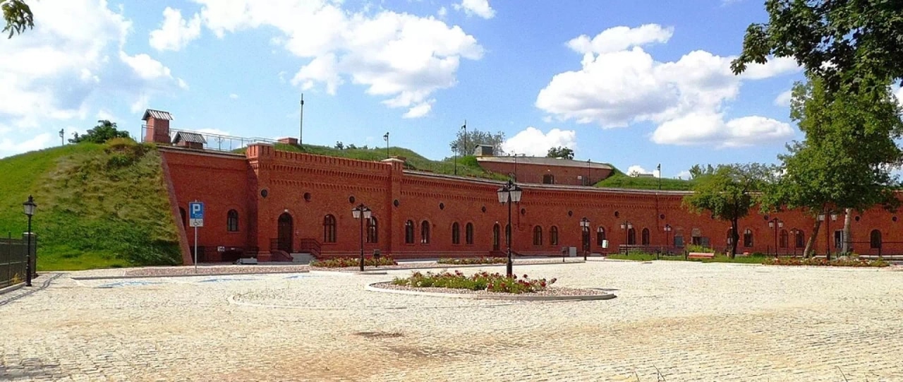 Rozległy i niski budynek z czerwonej cegły, który należy do Muzeum Twierdzy Toruń.