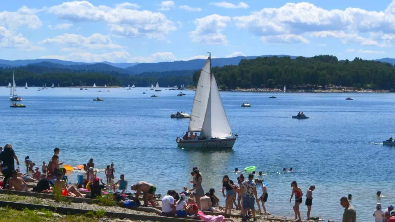 Ludzie na plaży oraz łódka na Jeziorze Solińskim