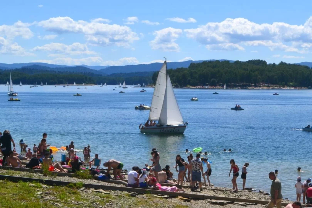 Ludzie na plaży oraz łódka na Jeziorze Solińskim