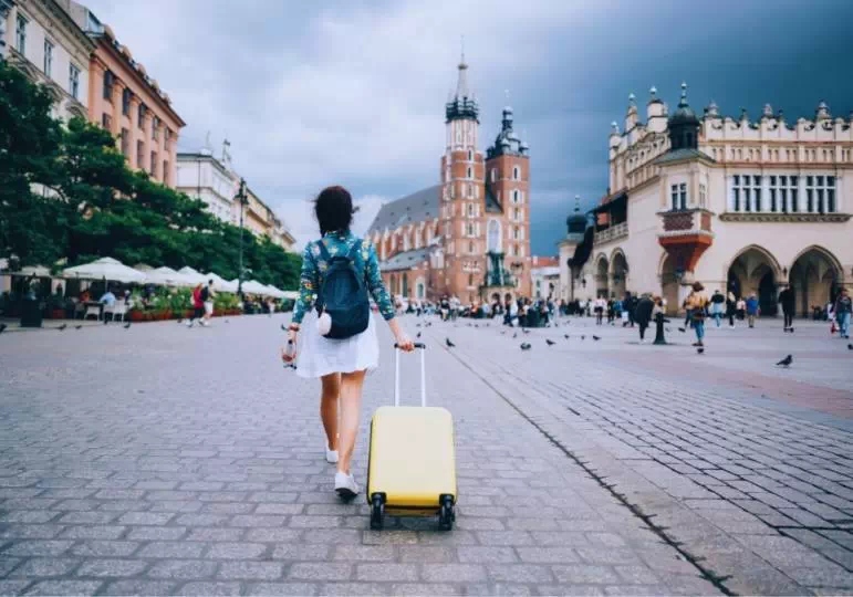 Kobieta idzie z walizką po krakowskim rynku