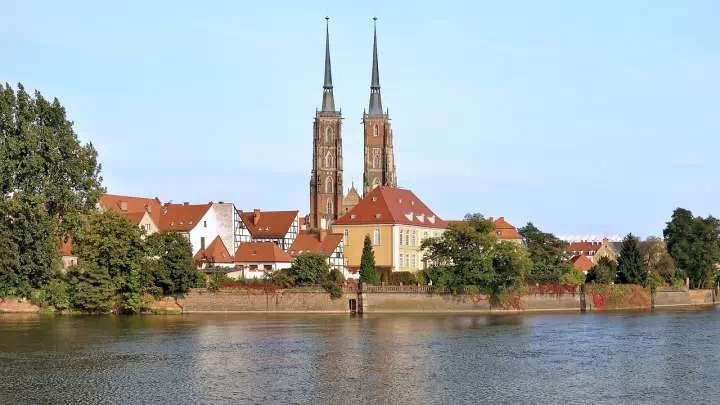 Dwie wieże kościelne, budynki i rzeka we Wrocławiu